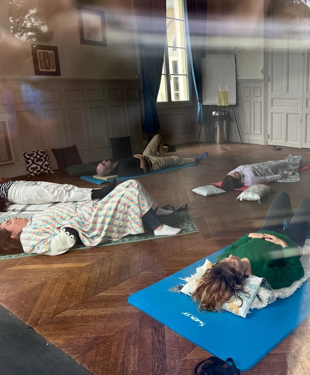 Cours collectif de Feldenkrais : élèves allongés sur des tapis dans une salle au parquet